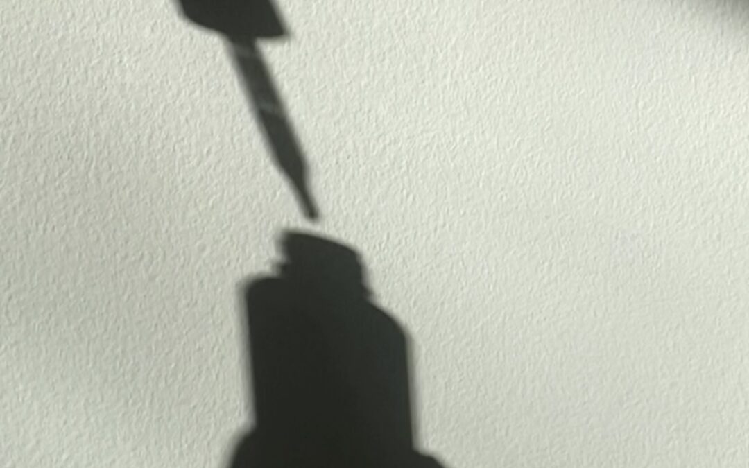 shadow of skincare drop with hands on white wall