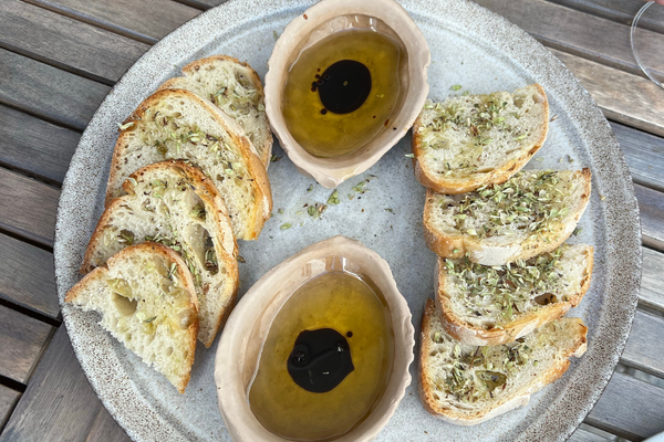 Olive oil served with bread and olives on a table